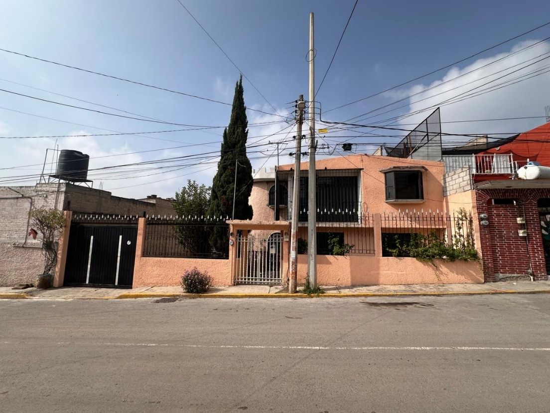 Fachada de la casa de dos niveles vista desde la calle, con portón y reja de acceso
