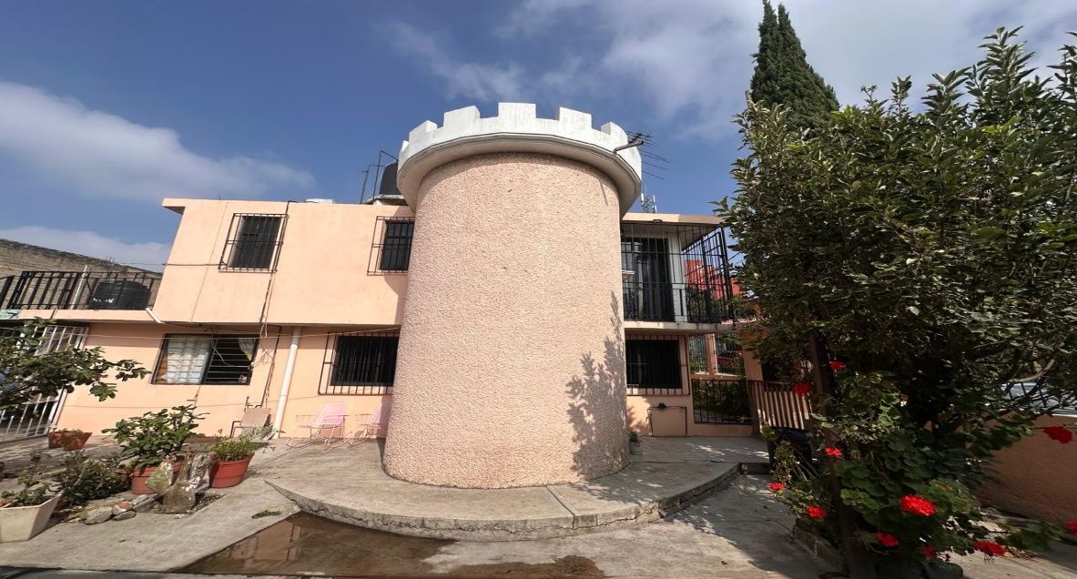 Torreón circular en el patio frontal, con jardín y macetas alrededor