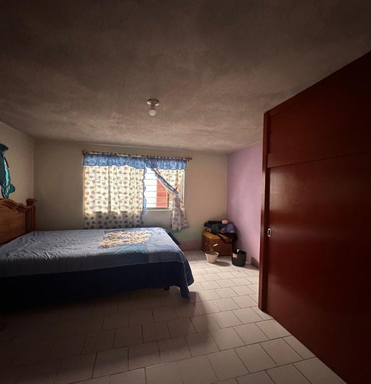 Recámara con clóset de puertas corredizas y ventana con cortinas