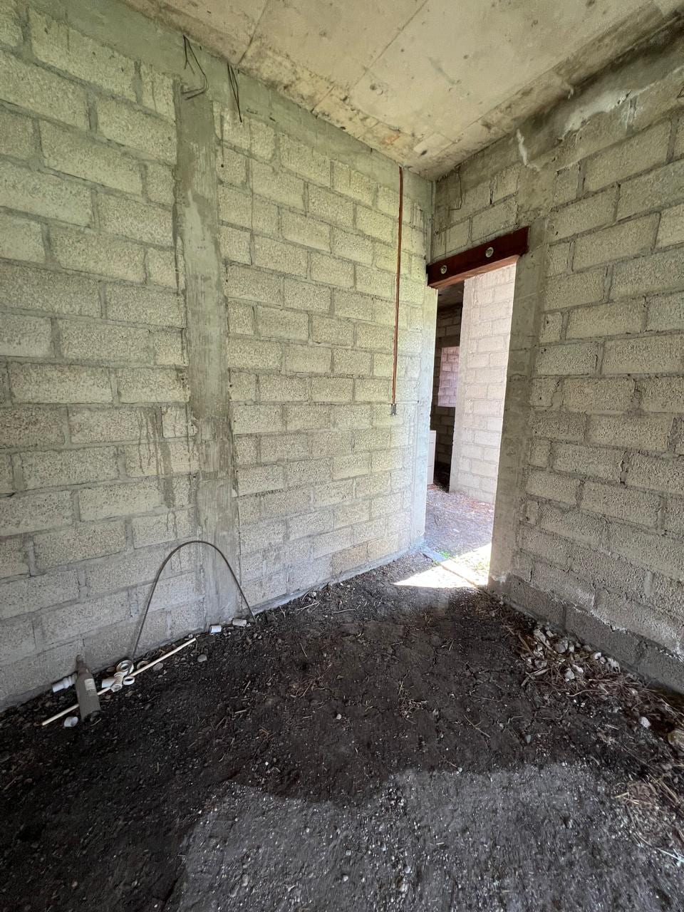 Interior en obra gris con vano de puerta y muros de block aparente