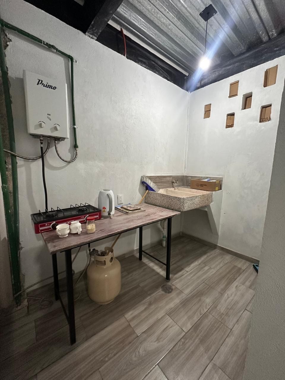 Cocina con tarja, calentador de paso y mesa con parrilla de gas