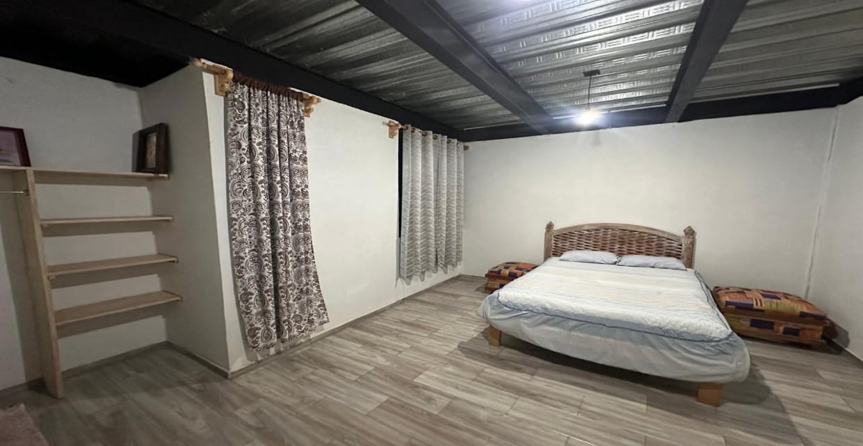 Habitación con ventana y repisas de madera, mostrada amueblada con cama matrimonial