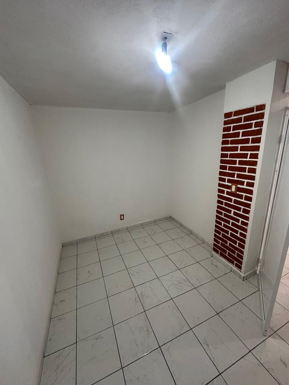 Recámara con columna de ladrillo aparente y piso de loseta clara
